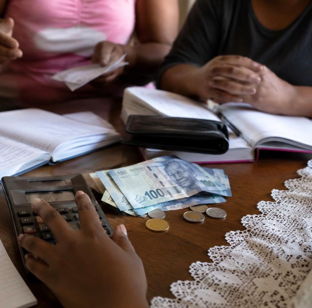 A stokvel meeting: cash, calculator and paper books on the table